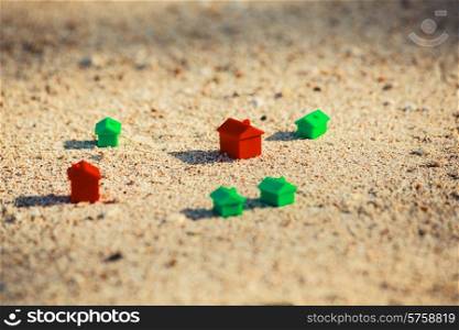Small red and green plastic houses in the sand on the beach