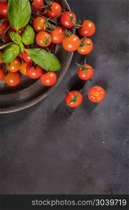 Small red cherry tomatoes on rustic background. Cherry tomatoes . Small red cherry tomatoes on rustic background. Cherry tomatoes on the vine witb basil leaves.