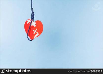 Small red heart shaped piece of paper on rope. Suicide, breakup, bad relationship, toxic romance, cardiology concept.. Heart on suicide rope
