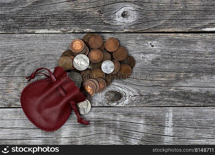 Small red leather bag of United States vintage coins on rustic wood background 
