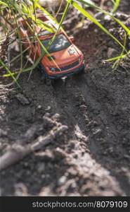 Small red off road car toy in the nature. Miniature