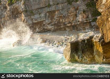 Small rocky beach and cliffs on the seashore. Early morning and surf splashes. Morning Rocky Shore and Splashes of Sea Surf