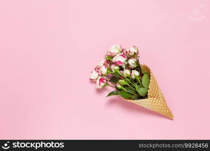 Small roses in waffle cone on pink background, copy space. Minimal style flat lay. For greeting card, invitation. March 8, February 14, birthday, Valentine"s, Mother"s, Women"s day concept. Top view.