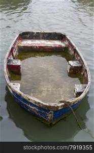 Small rowing boat half filled with water.
