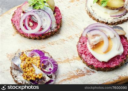 Small sandwiches or bruschettas with salted herring and beetroot.Open sandwich with salted herring. Bruschetta with salted herring