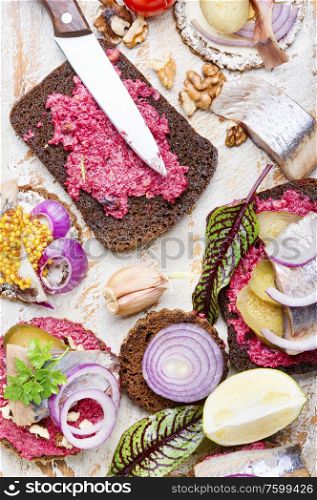 Small sandwiches or bruschettas with salted herring, beetroot and onions. Bruschetta with salted herring