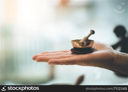 Small singing bowl holding in hand, blurry background