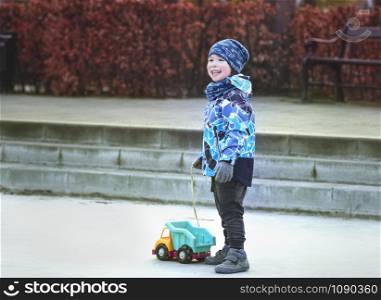 Small smiling boy holding toy truck