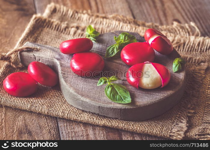 Small snack cheeses with fresh basil on the wooden board