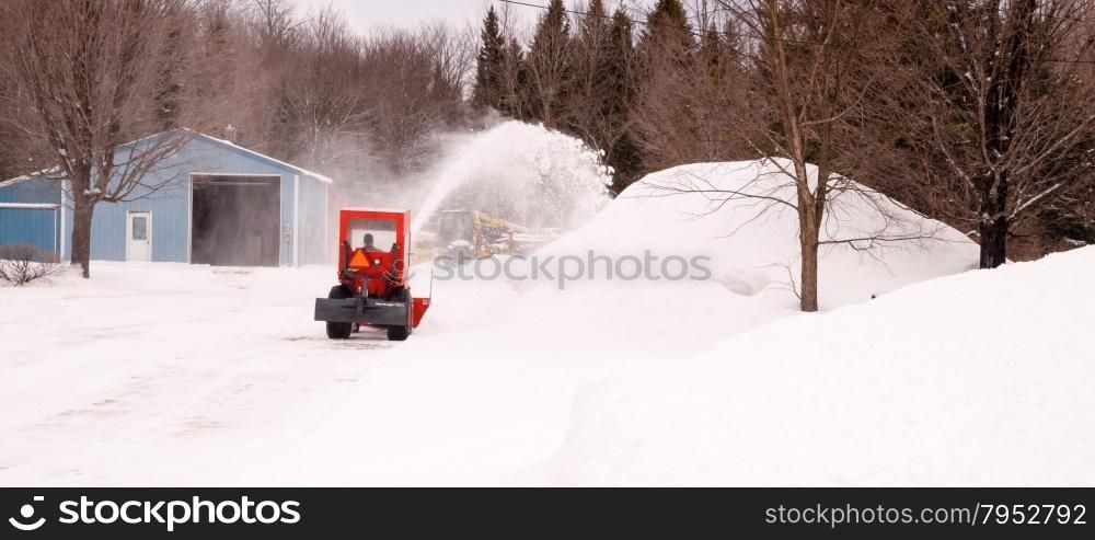 Small snowblowing tractor takes on the driveway after a long night of snowfall