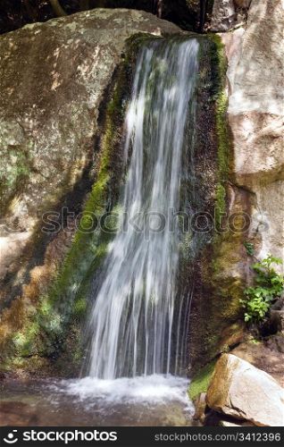 Small spring mountain waterfall and rock behind
