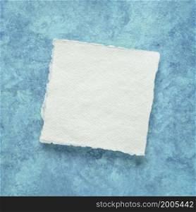 small square sheet of blank white Khadi paper against blue amate bark paper