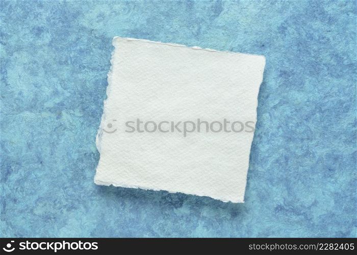 small square sheet of blank white Khadi paper against blue amate bark paper
