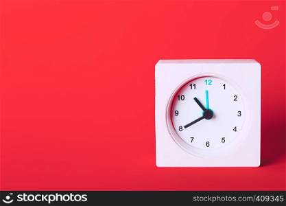 small square white clock on a red background