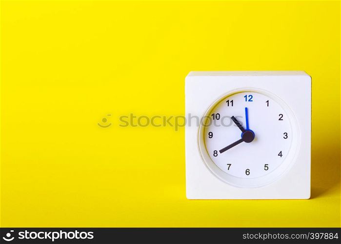 small square white clock on a yellow background