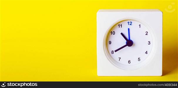small square white clock on ayellow background