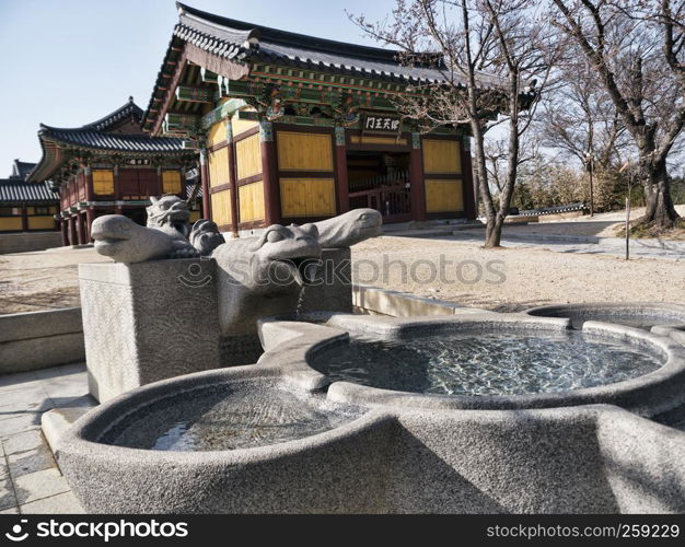 Small stone fountain and traditional asian houses on the background in Naksansa temple, Yangyang city, South Korea