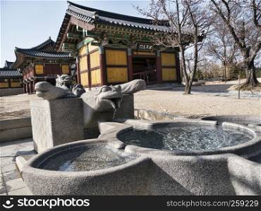 Small stone fountain and traditional asian houses on the background in Naksansa temple, Yangyang city, South Korea