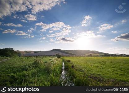 Small stream flowing through countryside landscape on Summer day