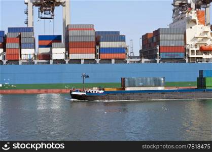 Small supply vessel passing a huge container ship, loaded with containers