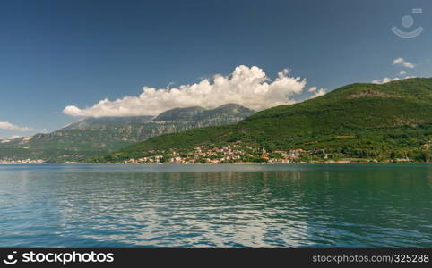 Small tourist villages on the Bay of Kotor in Montenegro, in a sunny summer day. The beginning of the cruise from Tivat city.. Villages on the shore of Bay of Kotor in Montenegro.