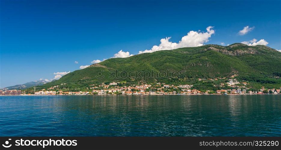 Small tourist villages on the Bay of Kotor in Montenegro, in a sunny summer day. The beginning of the cruise from Tivat city.. Villages on the shore of Bay of Kotor in Montenegro.