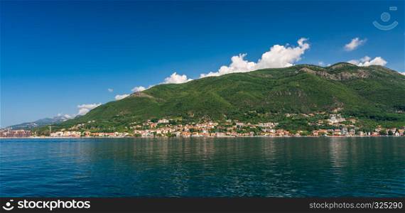 Small tourist villages on the Bay of Kotor in Montenegro, in a sunny summer day. The beginning of the cruise from Tivat city.. Villages on the shore of Bay of Kotor in Montenegro.