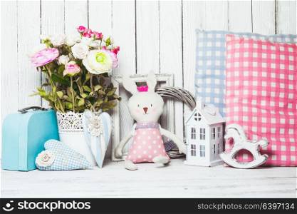 Small toy house, pony, toy bunny, pillows in the children&rsquo;s room on wooden background. Children room decor