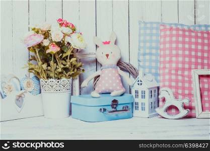 Small toy house, pony, toy bunny, pillows in the children&rsquo;s room on wooden background. Children room decor