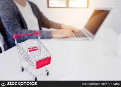 small trolley cart with woman enjoy shopping on her laptop background