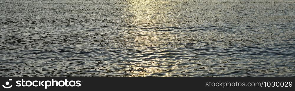 Small Water waves are moving in the river. Texture or background. Evening sun in river water. Long poster. Small Water waves are moving in the river. Texture or background. Evening sun in river water.