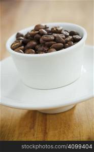 Small white cup filled with brown coffee beans