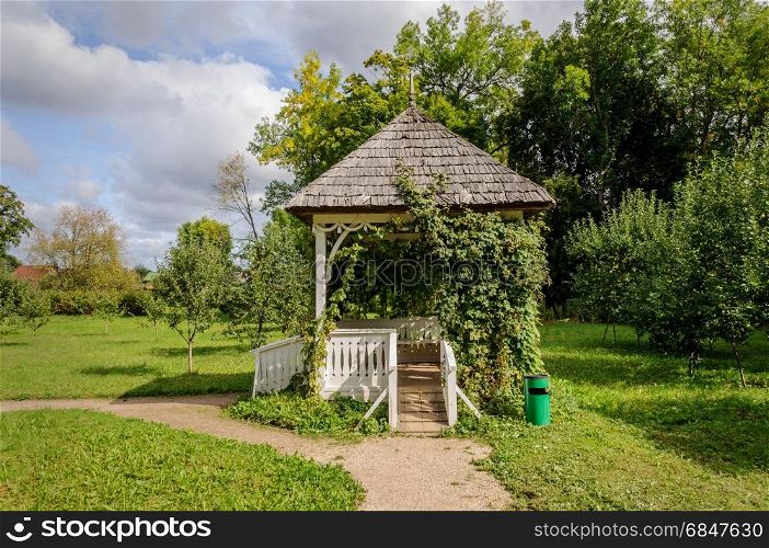 Small white wooden gazebo in park of Petrovskoe village. State Museum-reserve of A. S. Pushkin, Pskov Region, Russia.. Small gazebo in park