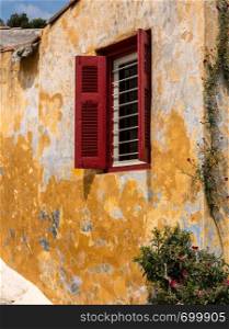 Small window in ancient neighborhood of Anafiotika in Athens by the Acropolis. Red shutters on window in ancient district of Anafiotika in Athens Greece