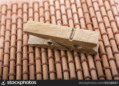 Small wooden clothespin placed on straw background