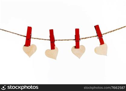 Small wooden hearts with red clothes pegs on a rope isolated on white background. Red hearts with clothes pegs on rope