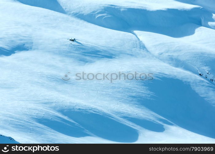 Small wooden house on winter mountain slope.