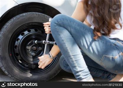 Smart and Attractive Asian woman jacks up her car and uses a wrench to change the wheel on a broken car, uses tools or equipment, tries to solve problems by self, Car Repairing and insurance concept