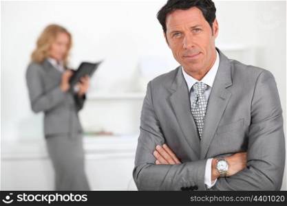 Smart businessman with a female colleague in the background