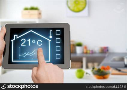 smart home and technology concept - close up of male hands pointing finger to tablet pc computer with house settings on screen over kitchen background. tablet pc with smart home settings on screen
