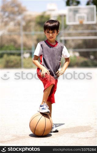 Smart kid holding basketball under his leg and posing in style in front of camera