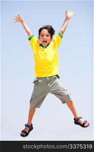 Smart kid jumping high in air, arms stretched and looking at camera