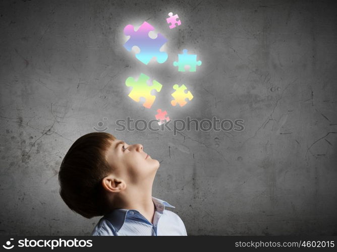 Smart kid. Young boy of school age looking at puzzle elements