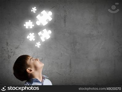 Smart kid. Young boy of school age looking at puzzle elements