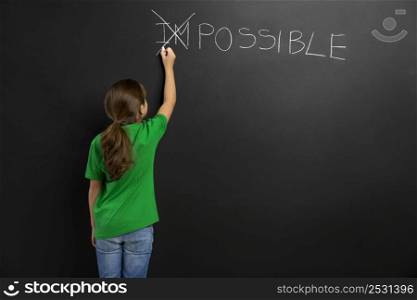 Smart little girl writing in a blackboard, with copy space