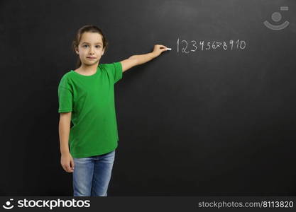 Smart little girl writing in a blackboard, with copy space