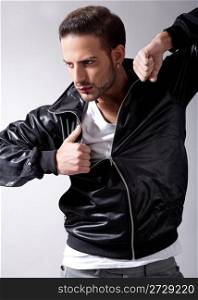 Smart male model giving movement with black jacket on a isolated grey background