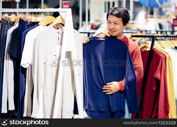 Smart man with beard try clothes in clothing store at shopping center, looking and choosing for new shirts design, Fashion and Consumerism Concept.