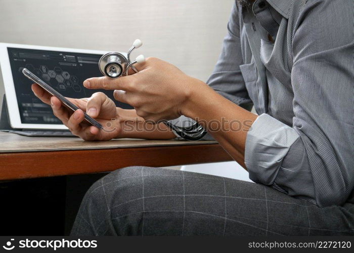 smart medical doctor hand working with smart phone,digital tablet computer,stethoscope eyeglass,on wood desk