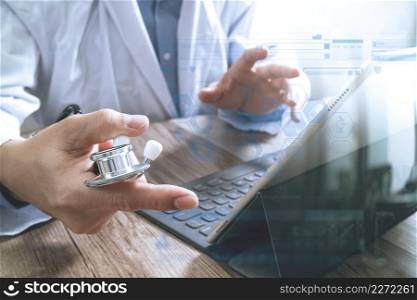 smart medical doctor hand working with smart phone,digital tablet computer,stethoscope eyeglass,on wood desk,icons graphic screen effect